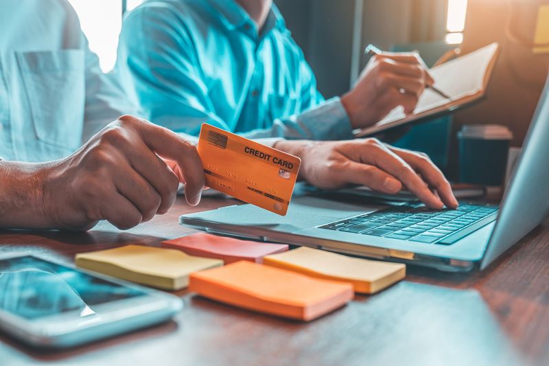 Person working on a computer holding a credit card